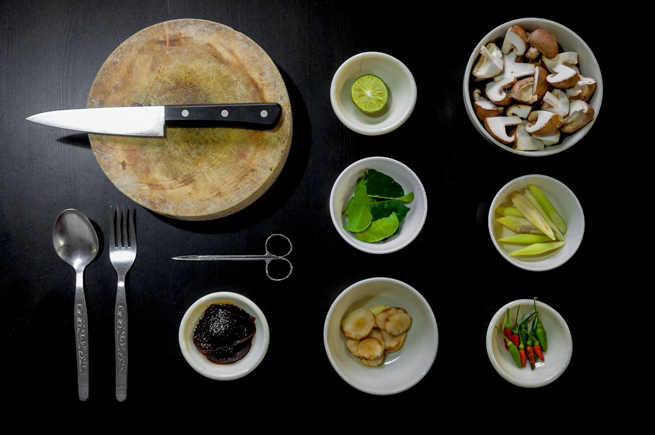 Aerial view of various cooking ingredients and utensils on dark background.