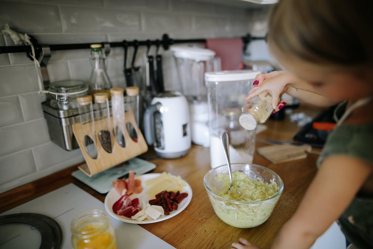Crafting Captivating Headlines: Your awesome post title goes here A young girl adds seasoning to a bowl in a well-equipped modern kitchen, engaging in cooking activities.