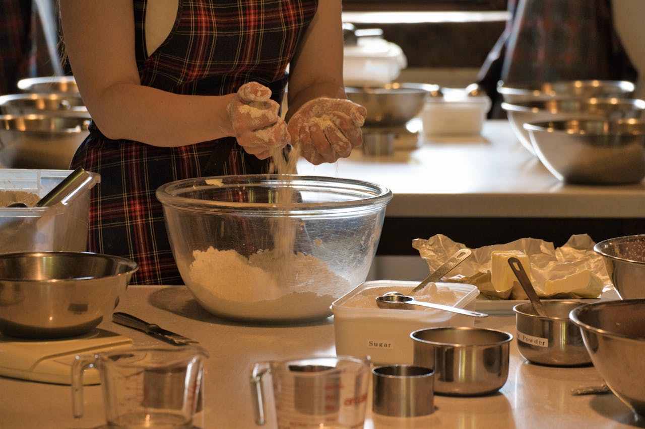 Close-up of a woman mixing ingredients in a bowl during a baking class with various kitchenware.